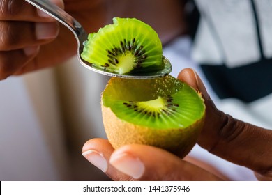 Kiwi Fruit In Hand. Girl Eating Ripe Kiwi With Tea Dessert Spoon.Summer Fruit For Healthy Diet And Vitamin C Concept