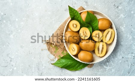 Kiwi gold fruits in a white bowl. Tropical fruits. On a gray concrete background. Top view.