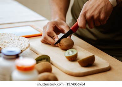 Kiwi For Salad. Close Up Of Dark-skinned Man Cutting Kiwi For Fruit Salad In The Morning