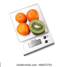Kiwi and tangerines on digital kitchen scales, isolated on white