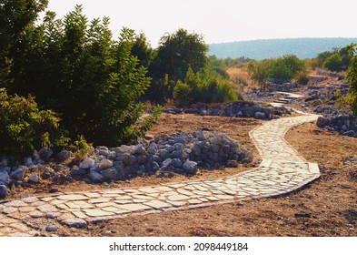 Kizkalesi,Turkey-October 11,2021:Scenic ancient winding cobble stone pathway along the ruins of antique buildings. Kanlidivane ancient city in Mersin Province, Turkey. Travel and tourism concept.