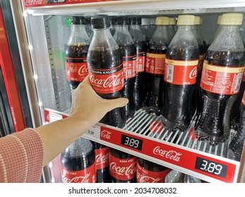 Klang, Malaysia - 28 August 2021 : Hand Pick Up A Coca-Cola Soft Drink Bottle Inside The Fridge In The Supermarket With Selective Focus.