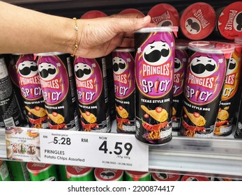 Klang, Malaysia - 28 August 2022 : Hand Pick Up A Tube Of PRINGLES Spicy Texas Style BBQ Potato Chips For Sell On The Supermarket Shelf With Selective Focus 