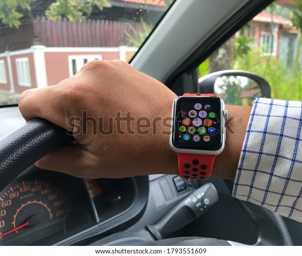 Klang, Selangor,\
Malaysia : 10th August 2020 - Man hand showing the apple watch with\
hold a car steering\
wheel.