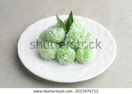 Klepon is Indonesian popular traditional snack, made from glutinous rice flour which is formed into small balls and filled with brown sugar. Finally covered with grated coconut. Served in white plate
