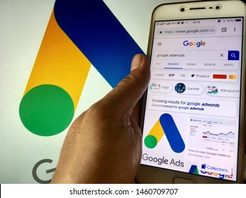 Kluang, Johor / Malaysia - July 25, 2019 : A Man Holding The Google Ads Searching Smartphone In Google Ads Wallpaper On Macbook Pro. Google Ads Is An Online Advertising Platform Developed By Google.