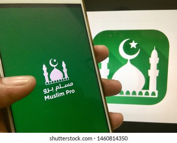 Kluang, Johor / Malaysia - July 25, 2019 : A Man Holding The Muslim Pro Apps In Front Muslim Pro Wallpaper On Macbook Pro. Muslim Pro Is The Best Islamic Apps.