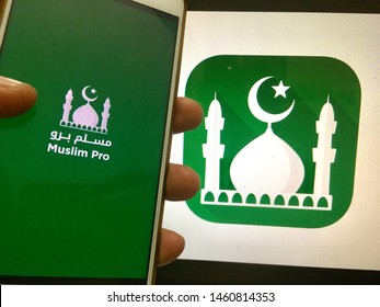 Kluang, Johor / Malaysia - July 25, 2019 : A Man Holding The Muslim Pro Apps In Front Muslim Pro Wallpaper On Macbook Pro. Muslim Pro Is The Best Islamic Apps.