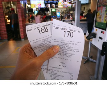 Kluang, Johor / Malaysia - June 16, 2020 : Hand Holding Two Receipt Show Order Number To Recieve A Food At Mc Donald Restaurant.