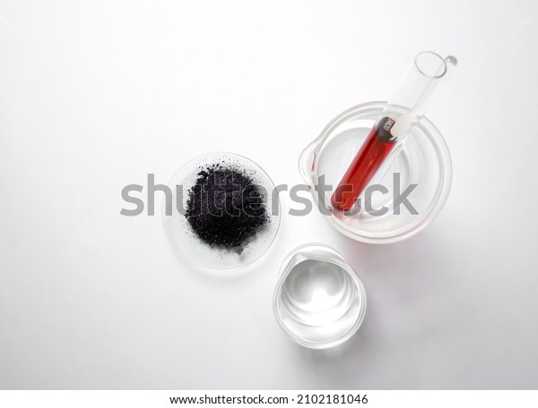 KMnO4 in chemical watch\
glass place next to Potassium Permanganate Liquid in test tube and\
alcohol in beaker. Medical Chemicals ingredient on white laboratory\
table. Top View