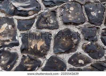 Knapped flint stone wall close up, rough texture and pattern