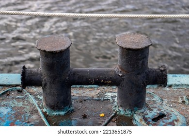 Knecht For Mooring And Fastening Of Mooring Cables. Black Farm Laborer Without A Rope On An Iron Deck, Side View. The Bollard Is A Pair Of Cast-iron Pedestals. Close-up Of The Rigging Against The Back