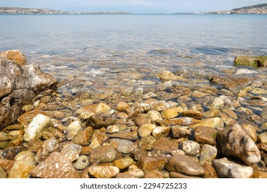 Knee feet ground level view of pebble stone rock sea beach seashore with faraway horizon and city.  Summer sea beach background concept. Nobody at the beach. Peaceful calm tranquility seaside concept. - Powered by Shutterstock