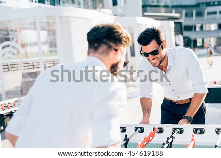Knee figure of two modern bearded businessman playing table football during a break - having fun, break, playing concept