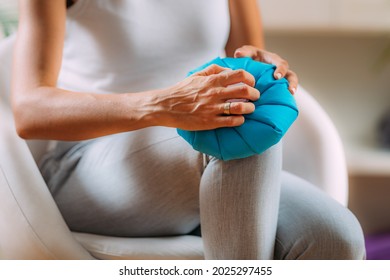 Knee pain treatment. Woman holding an ice bag pack on her painful knee 