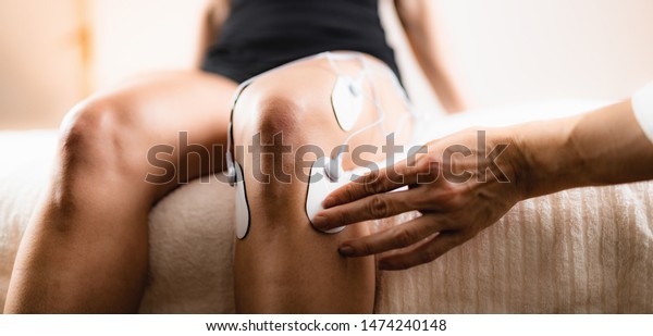Knee Physical Therapy with TENS Electrode\
Pads, Transcutaneous Electrical Nerve Stimulation. Therapist\
Positioning Electrodes onto Patient\'s\
Knee