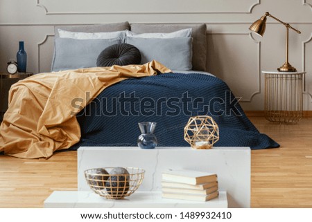 Knick knacks on console table in from of king size bed with comfortable bedding