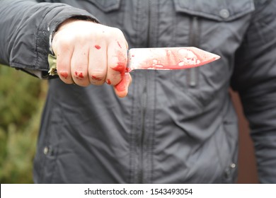 Knife Attack Concept. Murderer, Killer Is Attacking With Knife With Red Fake Blood Drops Outdoors 