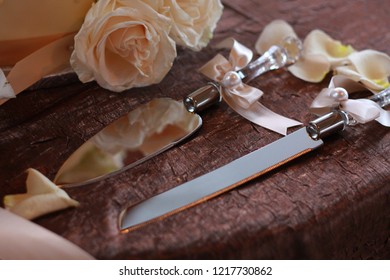 A Knife And Cake Cutter Sit On A Table At A Wedding Ceremony.