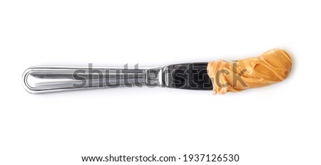 Knife with creamy peanut butter isolated on white background. Top view.