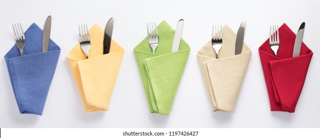 knife and fork in folded napkin at white background, top view