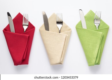 Knife And Fork In Folded Napkin At White Background, Top View