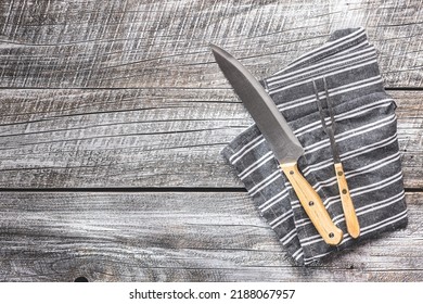 Knife And Fork On Napkin On A Wooden Table.