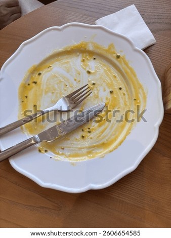 Knife and fork placed parallel on an empty white plate after a finished meal, indicating that the dish can be cleared, set on a restaurant table with a clean setting, concept of dining etiquette