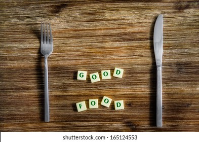 Knife And Fork Set On Wooden Vintage Table With Good Food Sign