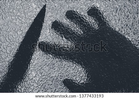 Knife in hand. Aggressive tin attack. Hacking attempt. The criminal behind the glass. Agony crooked hand. Criminal and victim, resisting the hands of the victim and attacking hand with a knife