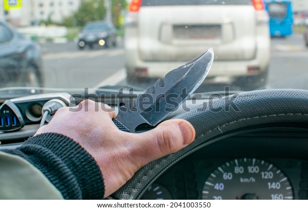 a\
knife in the hand of a driver behind the wheel of a car while\
driving around the city in a traffic jam. a maniac, a bandit, a\
murderer pursues the victim by following him in a\
car