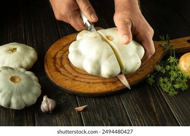 A knife in the hands of a chef slicing zucchini on a wooden board before preparing a tasty and healthy breakfast. - Powered by Shutterstock