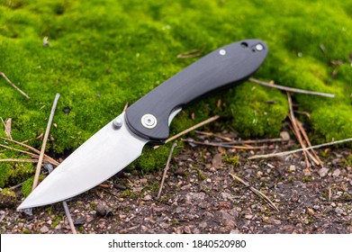 Knife on moss at an angle. The knife is in a tilted position. Front view.