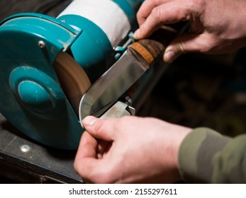 Knife sharpener and a hand with a blade, a man sharpens a knife on a grinder