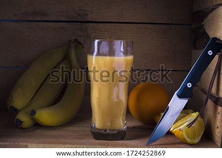 A knife with a shiny sharp blade. Fruit juice and fruits. Low key.