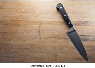 A Knife Sits To The Side Of A Butcher Block Counter Top