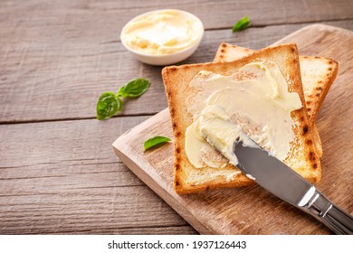 Messer, das Butter auf Toastbrot auf Holzhintergrund ausbreitet. Kopiert Platz.
