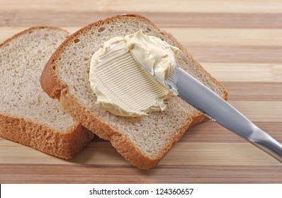 A Knife Spreading Butter On Wheat Bread