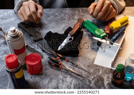 Knife in the workshop. Folding knives and tools. Knife cleaning and care. Hands and knife.