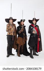 Knight of the road. Portrait of men in vitage costumes with swords, musketeer and pirate isolated on white background. Combination of medeival and modern styles. Concept of history. Copyspace for ad.