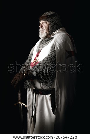 Knight Templar posing with sword in a dark background
