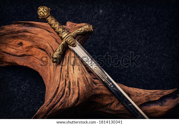 Knight\'s sword on the background of an old\
textured wooden driftwood of brown\
color
