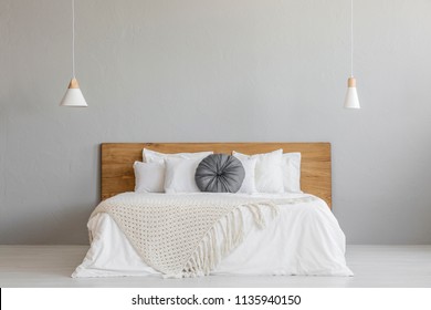 Knit Blanket On Wooden Bed Against Grey Wall In Minimal Bedroom Interior With Lamps. Real Photo With A Place For Your Nightstand