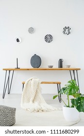 Knit Blanket On A Wooden Bench In Minimal Interior With Vase On The Table Against White Wall With Plates