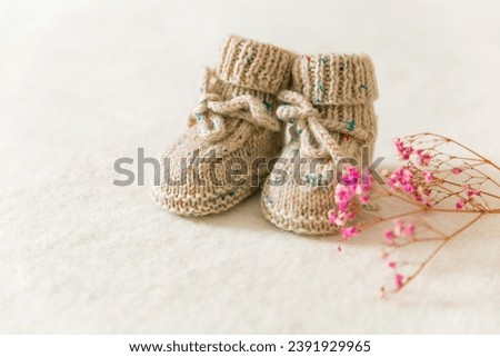Knitted baby socks, booties on a white background with copy space. Pregnancy and motherhood concept, first birthday banner, handmade socks, baby warm clothes, handmade knitted socks, hobby.