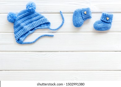 Knitted Blue Footwear And Hat For Baby On White Wooden Background Top View Mockup