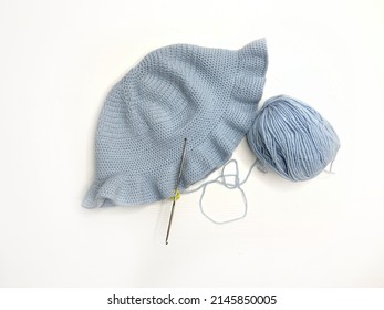 Knitted Blue Hat And Crochet Tools On White Background