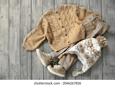 Knitted cardigan,  jeans and hat flat lay on wooden background. Baby autumn clothes. Boy's apparel set.Child's clothing top view.Outlook collection vintage wear.