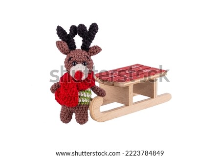 Knitted Christmas deer toy and wooden sleigh isolated on white background.