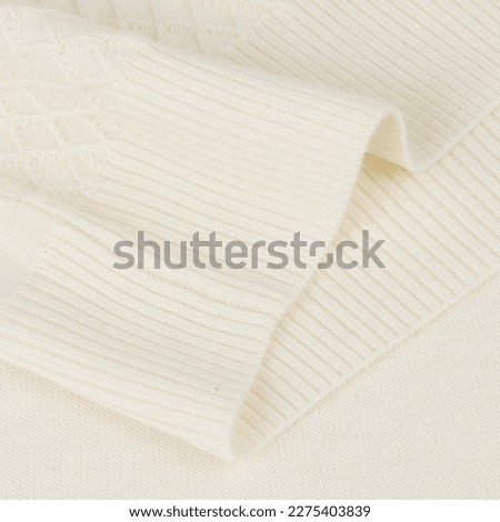Knitted elastic band on creamy white wool jumper background close up